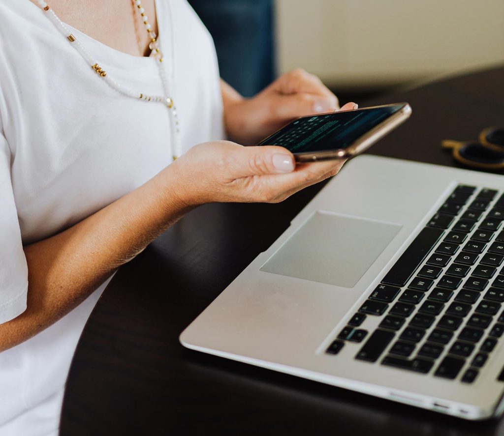 A person using their phone by a laptop