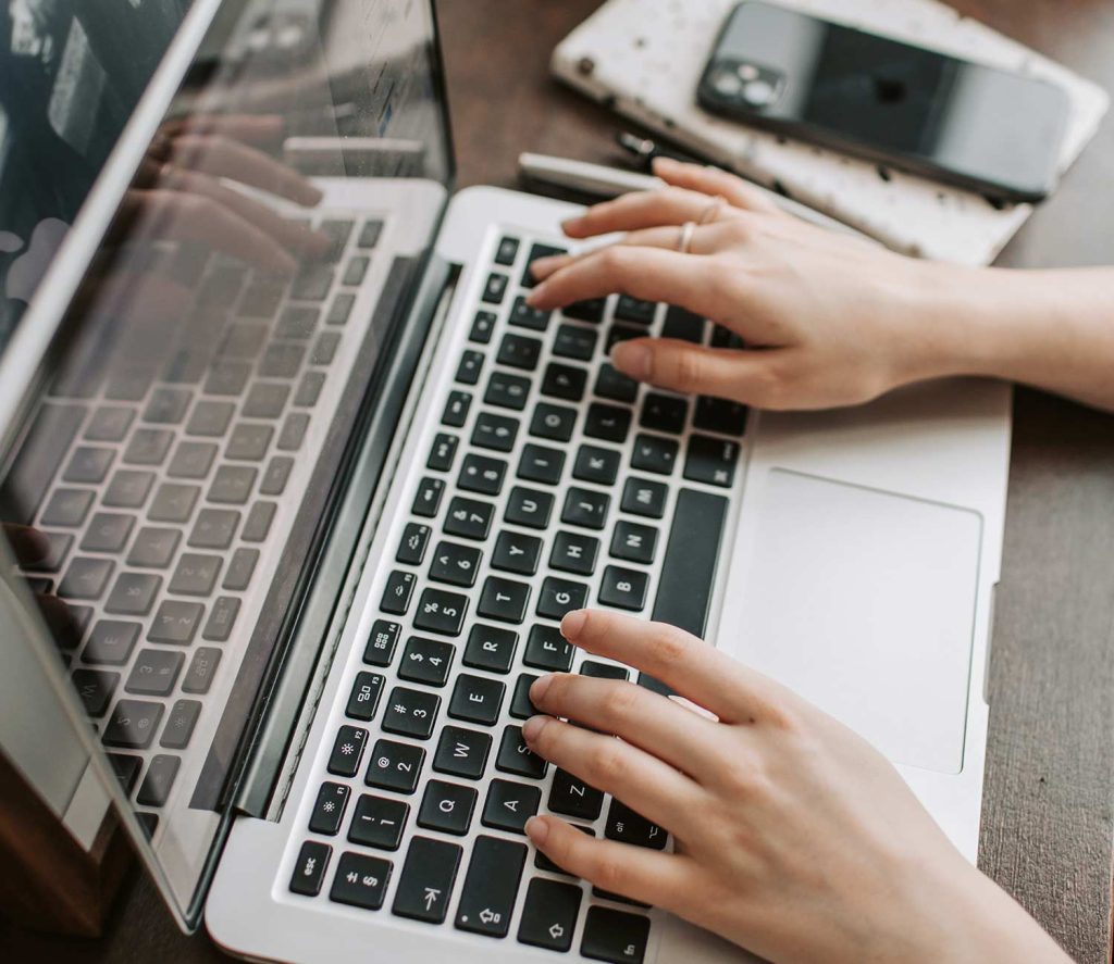 A person hands typing on a computer keyboard