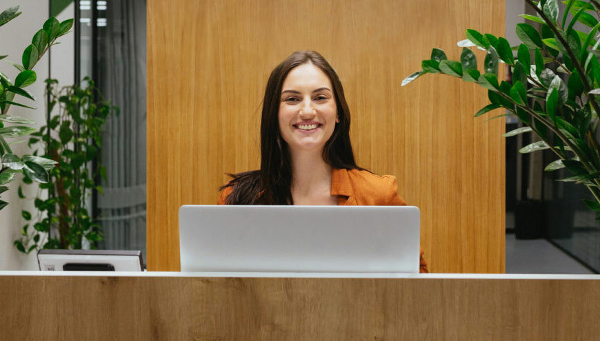 Woman Smiling Behind a Hotel Checkin Desk